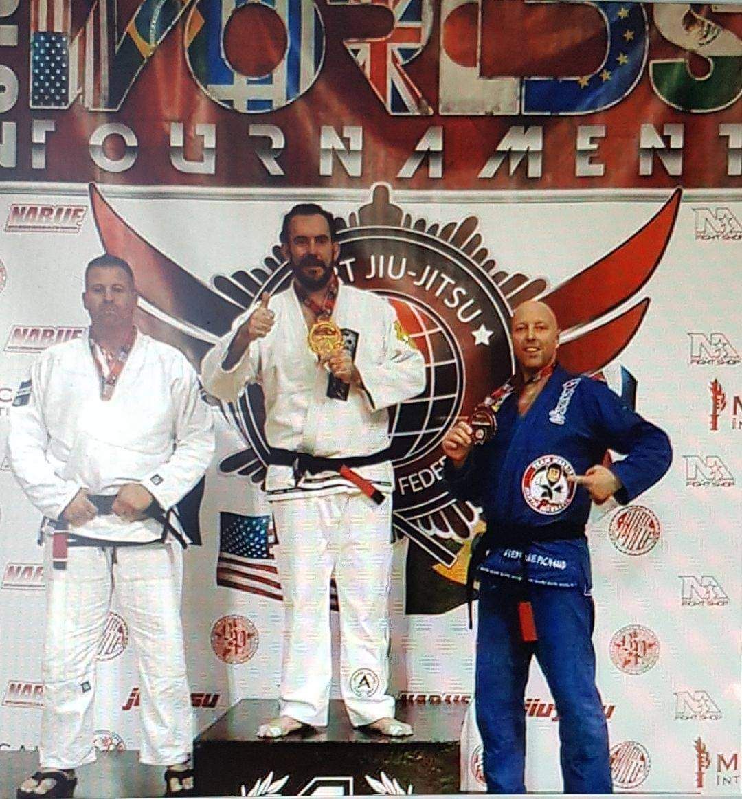 Stéphane Pichaud, en kimono bleu, médaillé sur le podium d'un tournoi mondial de jiu-jitsu.